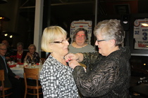 Aila Nylund sai kultaisen ansiomerkin Ulla Pullolalta, Petra Toivosen EKL:stä seuratessa seremoniaa.